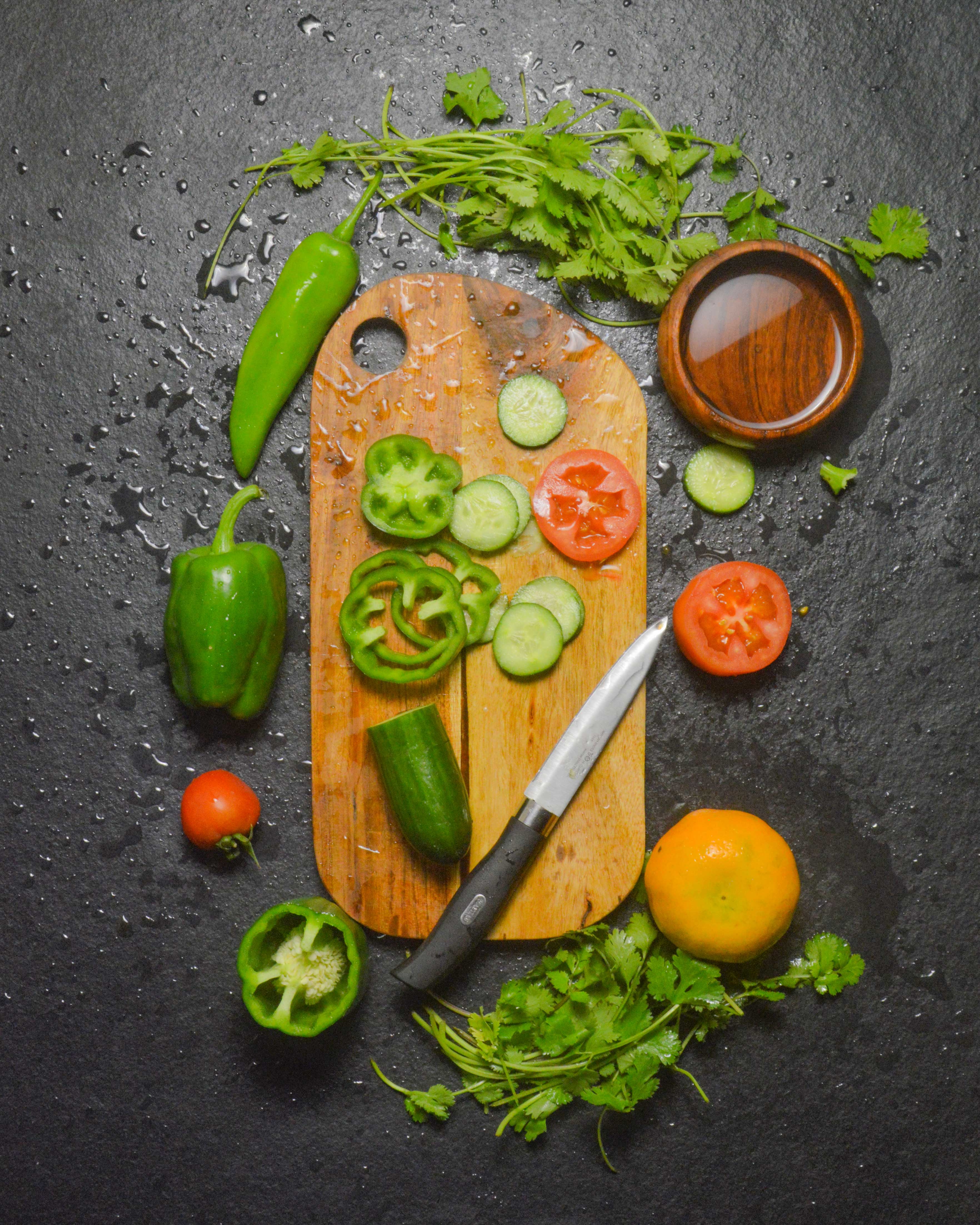 Wooden cutting board with sliced vegetables and knife - artisan food preparation board for cooking