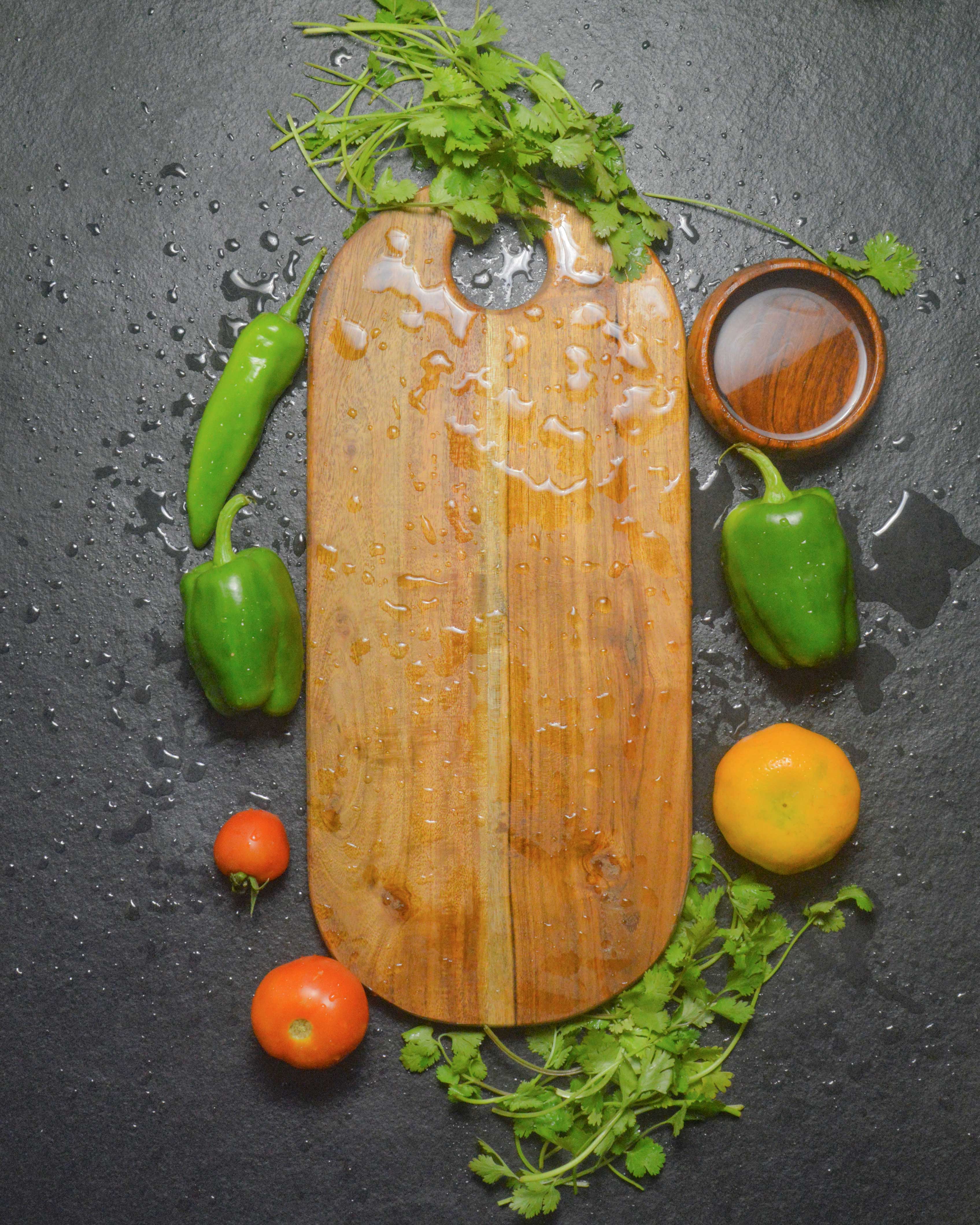 Artisan wooden chopping board with fresh vegetables and oranges - handcrafted cutting board for food prep and serving