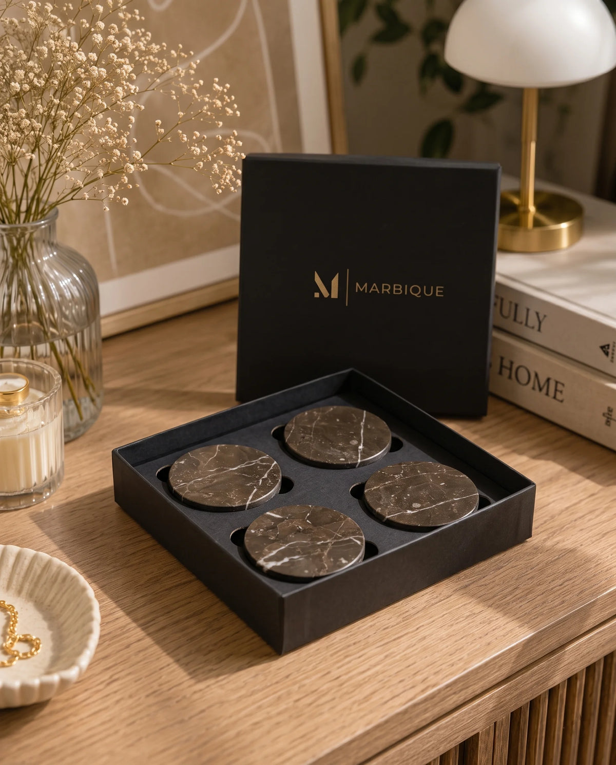 Four dark brown round coasters with pale veining arranged in an open black Marbique box.