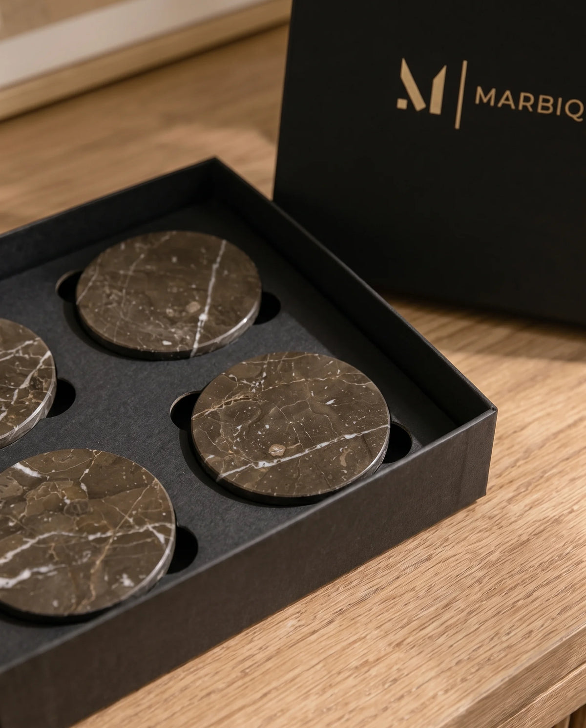 Dark brown circular coasters with pale veins styled on a table with drinkware.