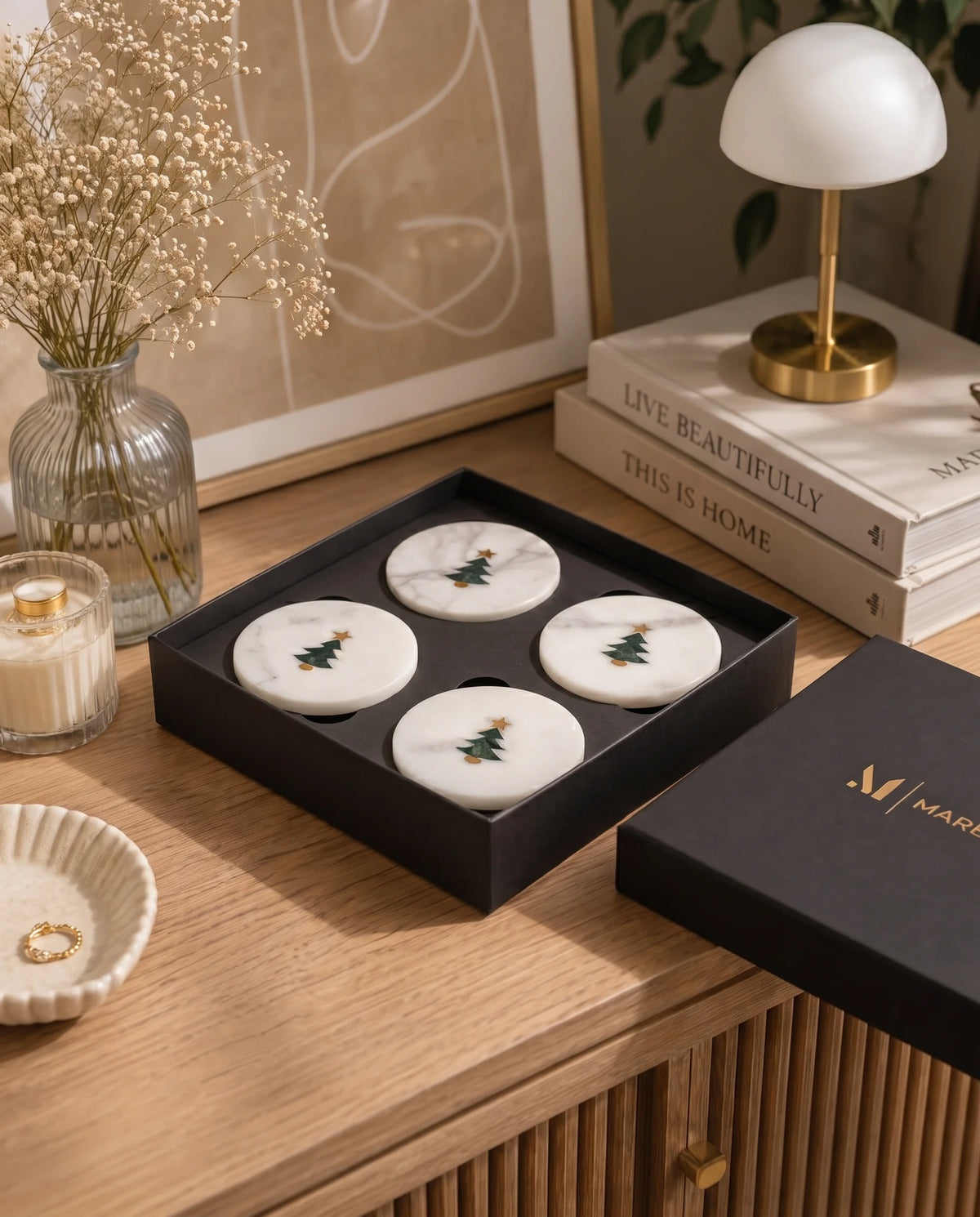 White round coasters with green Christmas trees and gold-tone stars arranged in a black Marbique box.