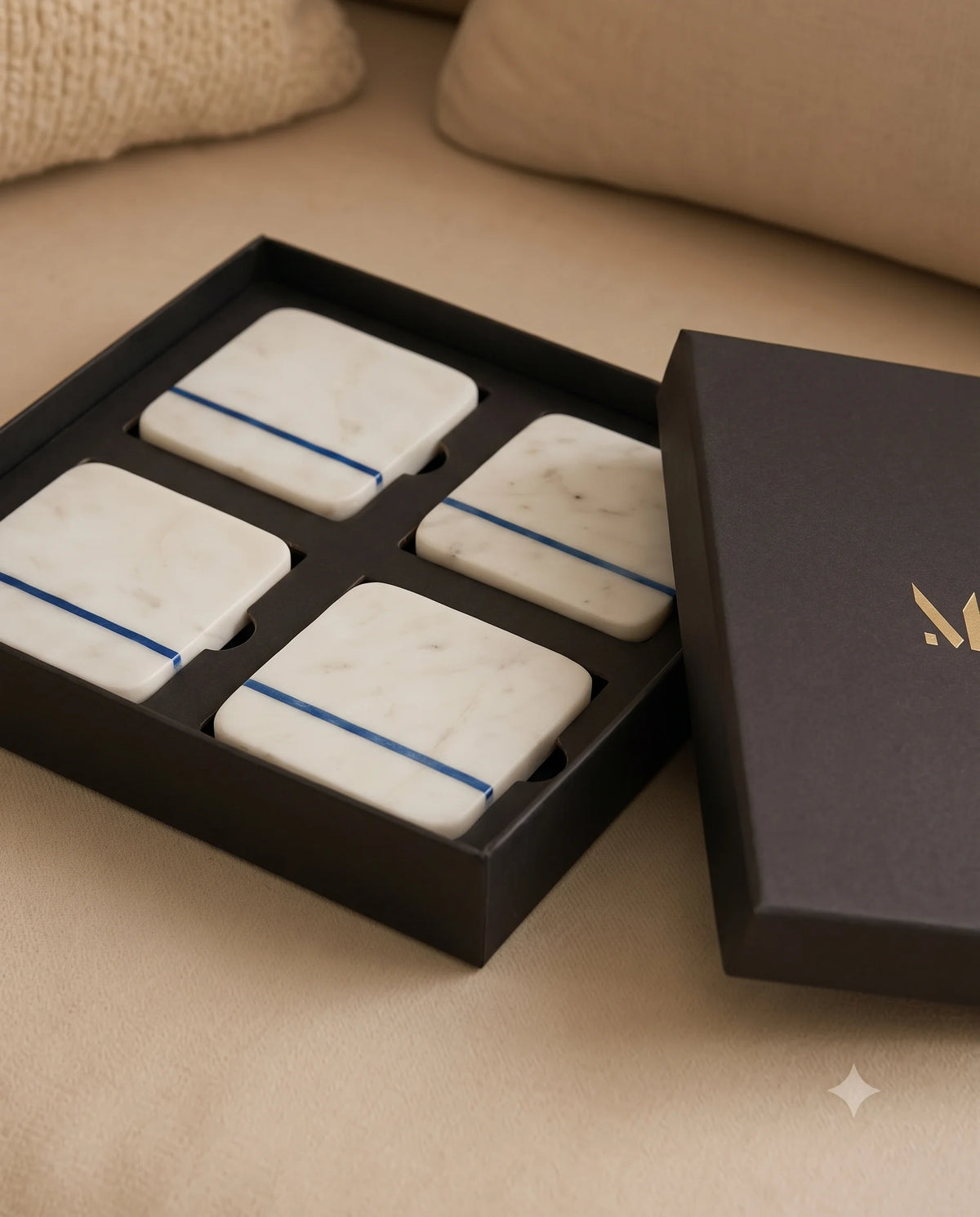 White square coaster designs with blue stripe details displayed with Marbique packaging.