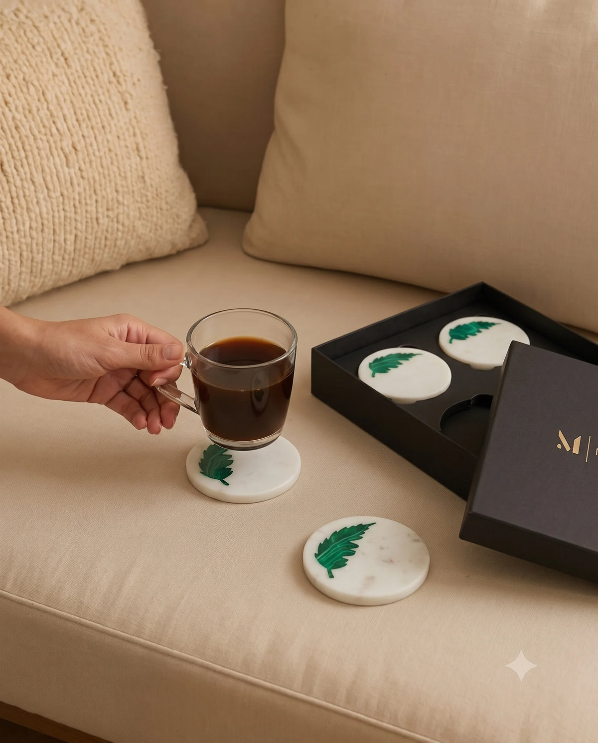 White circular coasters with green leaf details styled with drinkware.