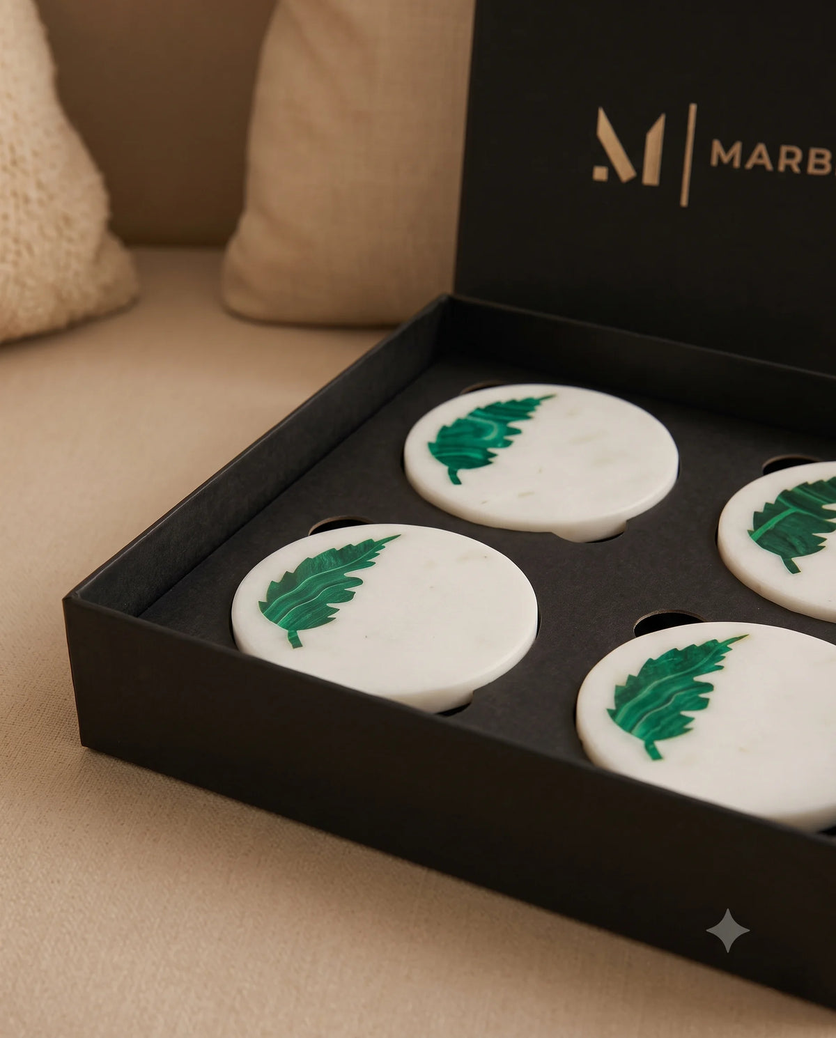 Close view of the green leaf motif on a white round coaster surface.