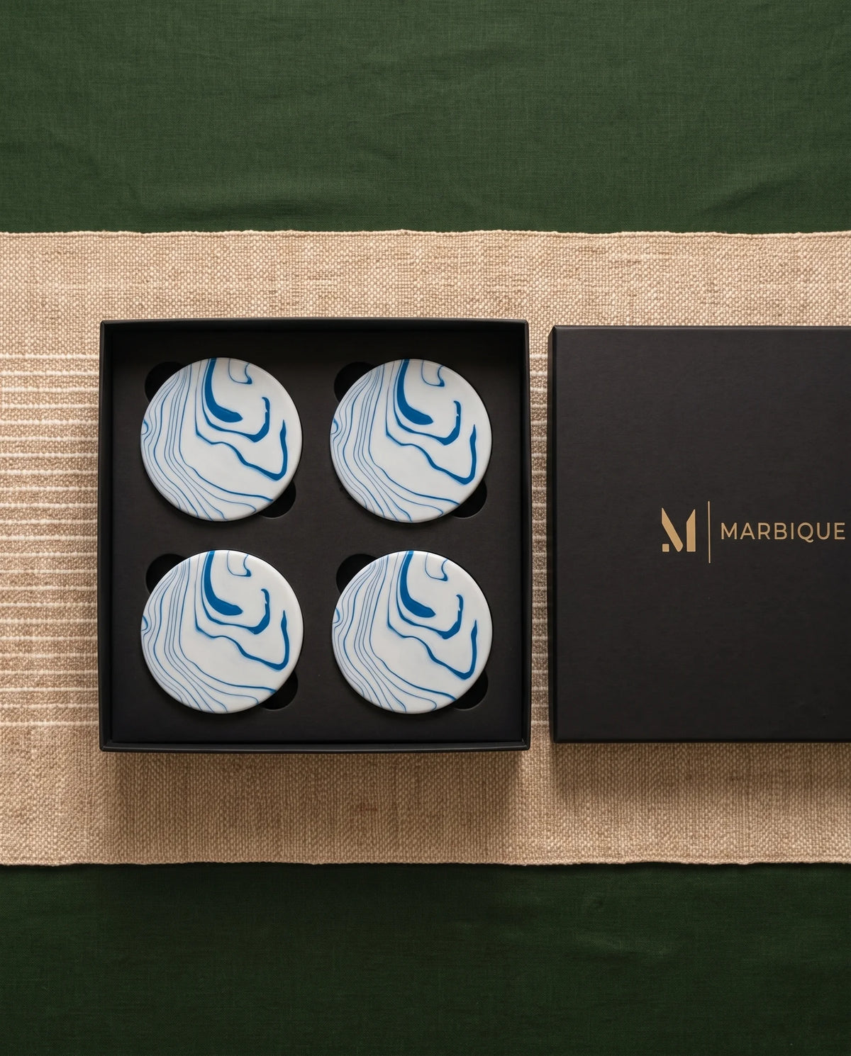 Black round coasters with white moon-phase motifs displayed in an open black Marbique box.