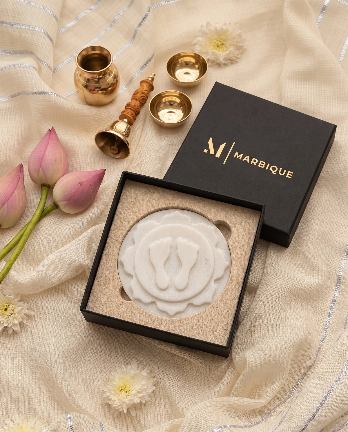 White circular pooja plaque with raised footprints, a layered floral motif and soft grey veining.