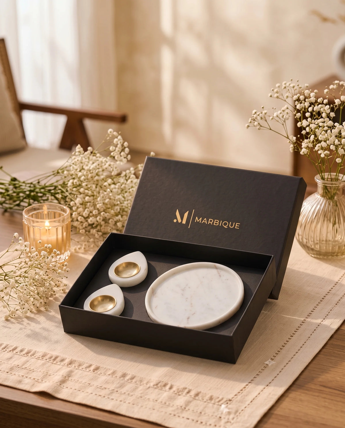 White round dish and two teardrop holders with gold-tone cups in an open black Marbique box.