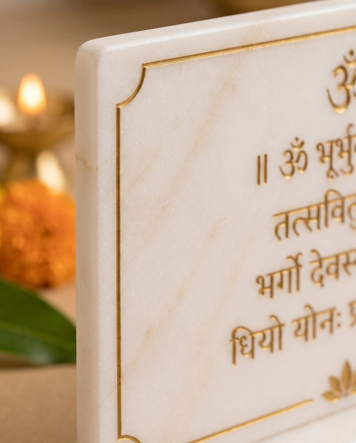 Close-up of the white mantra plaque showing the gold-tone border corner and Devanagari lettering.