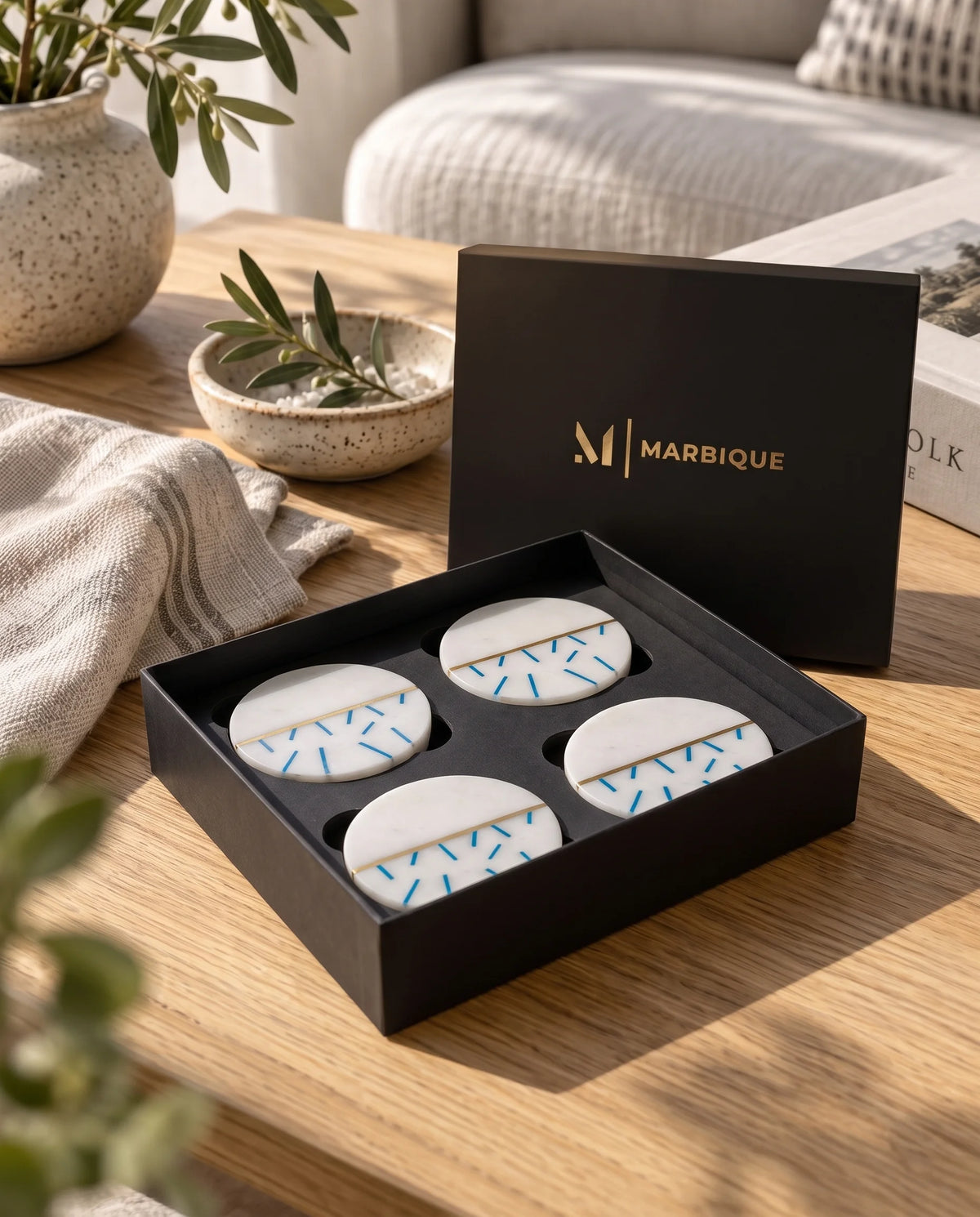 White circular coaster design with scattered blue dashes on part of the surface and a slim gold-tone divider.
