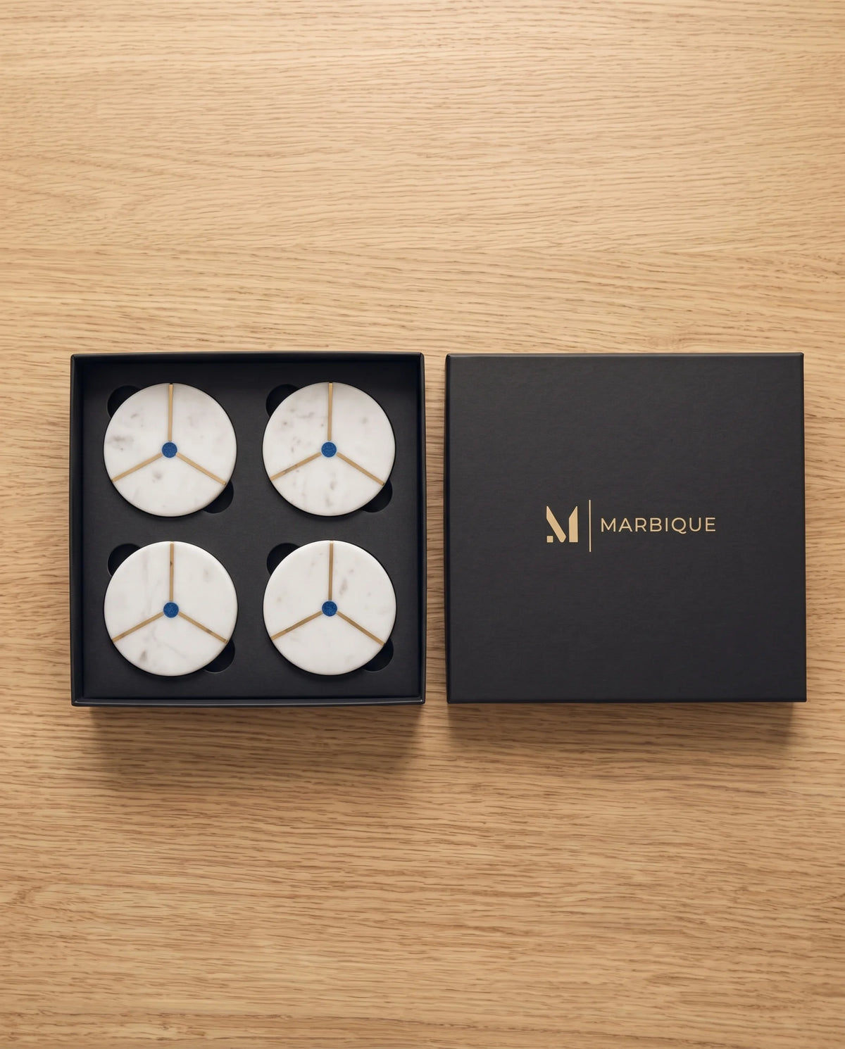 White round coasters with a black diagonal band edged in gold-tone lines.