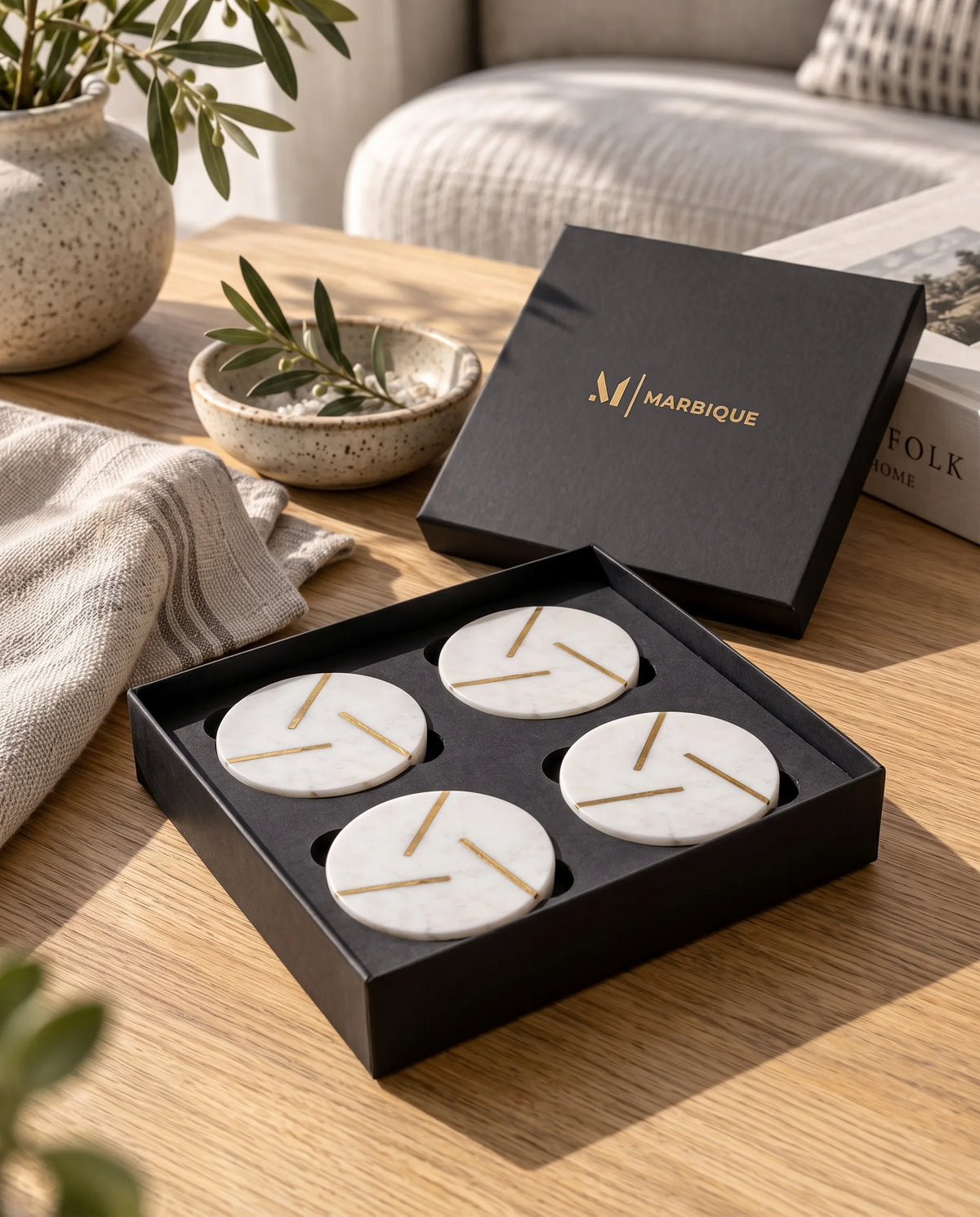 White round coaster designs with gold-tone geometric lines, styled with drinks on a wooden table.