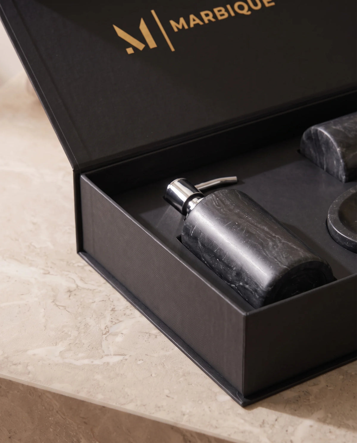 Close-up of a charcoal dispenser and matching accessories arranged in a black Marbique box.