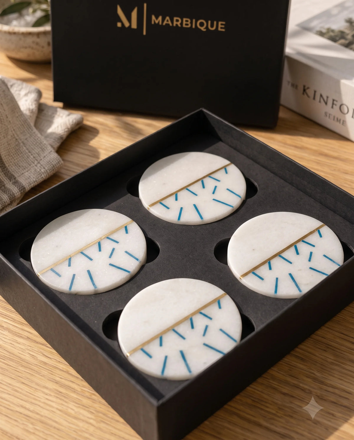 White round coaster with a partial blue dash pattern and gold-tone line detail in a drinks setting.