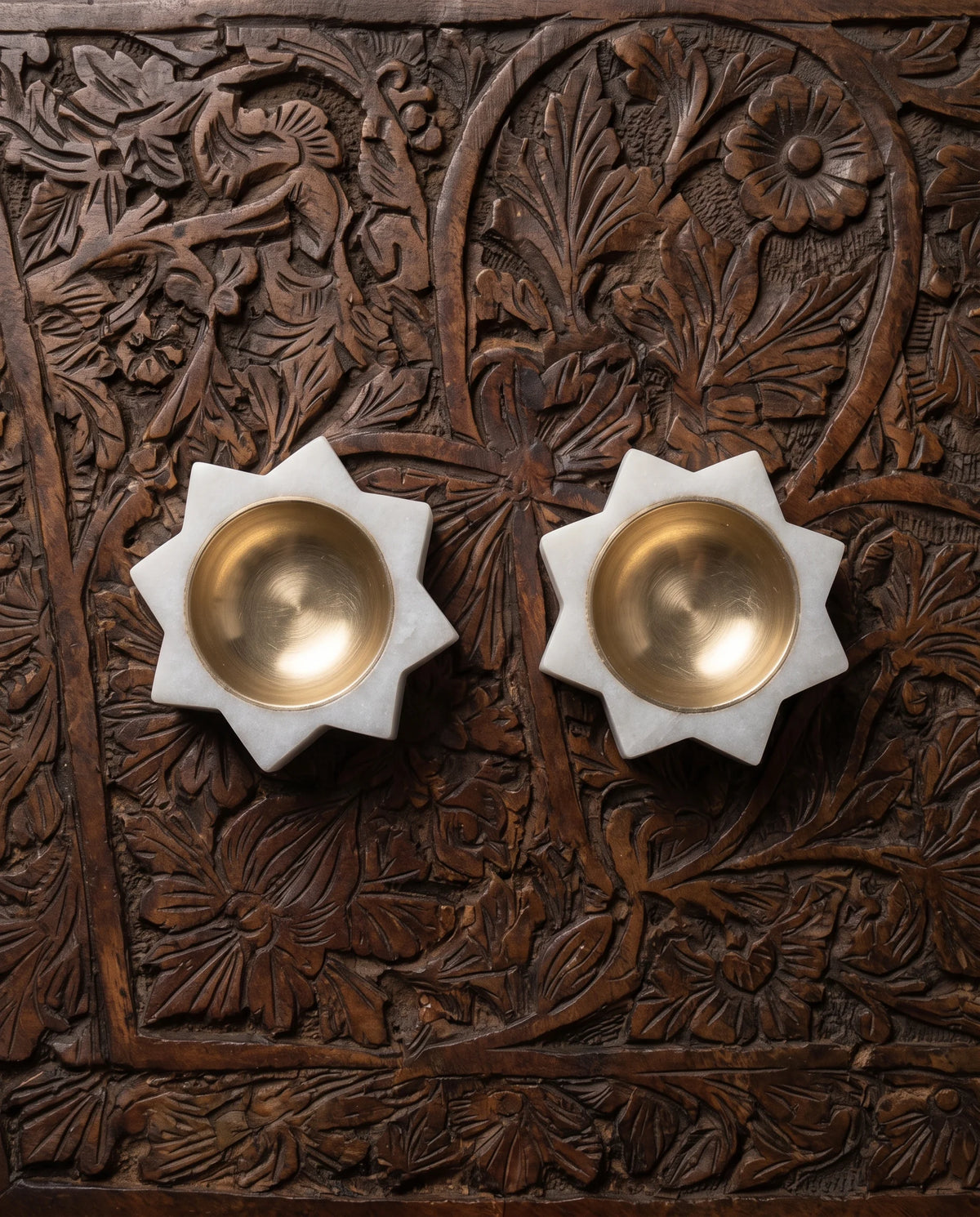 Overhead view of two white pointed-star holders with circular gold-tone cups.