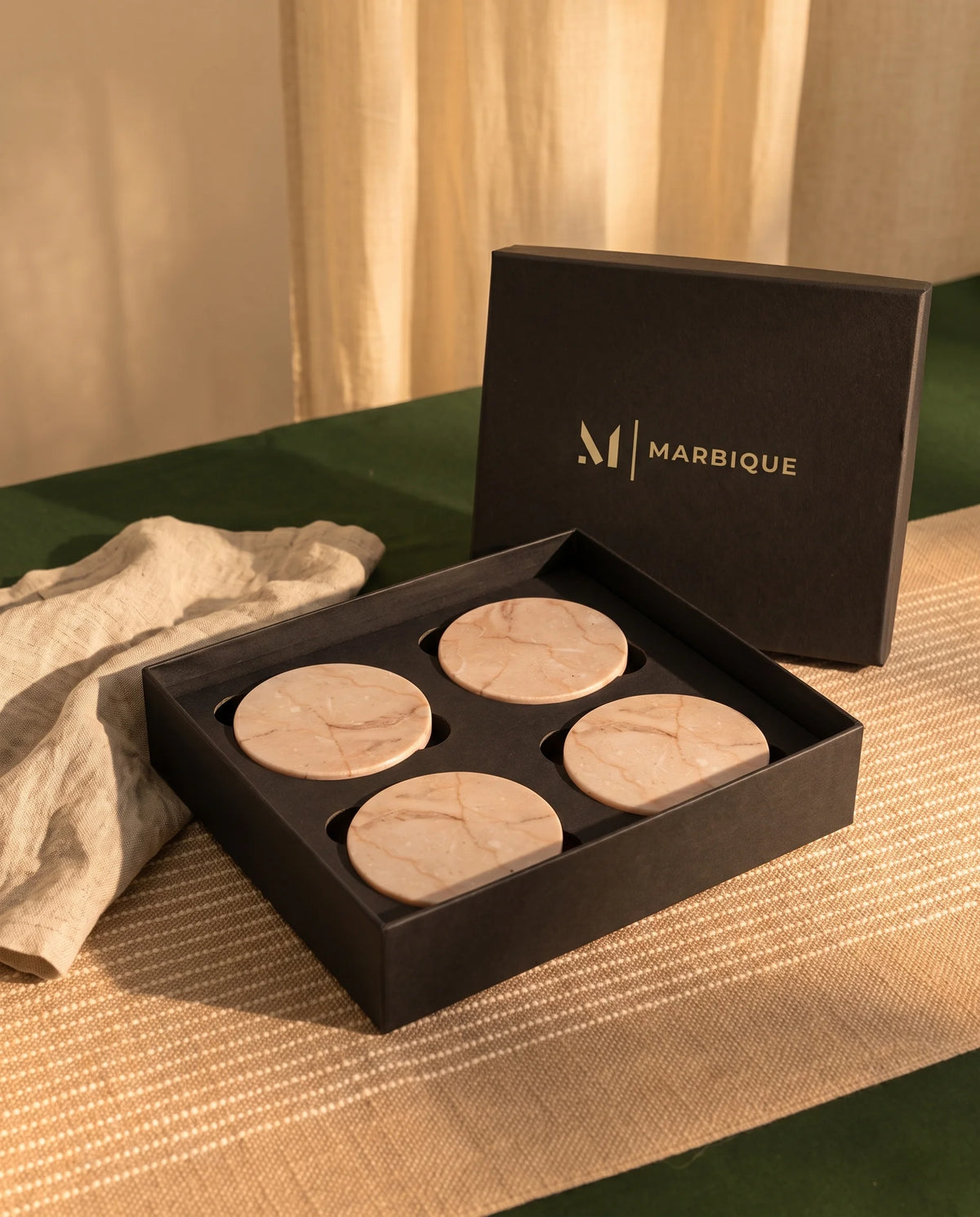 Round light beige coaster with subtle tan veining, styled with drinkware.