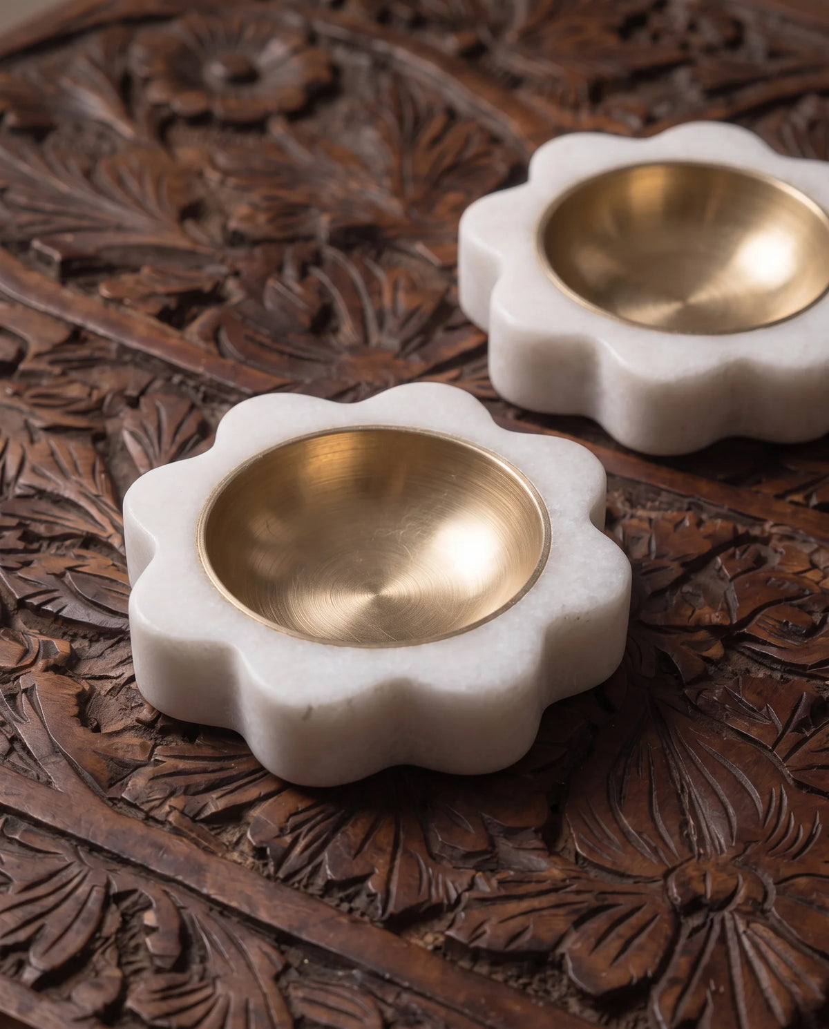 Close-up of white rounded-petal diya-holder bases surrounding circular gold-tone cups.
