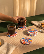 Multicolour circular coaster with an abstract swirl pattern in a drinks setting.