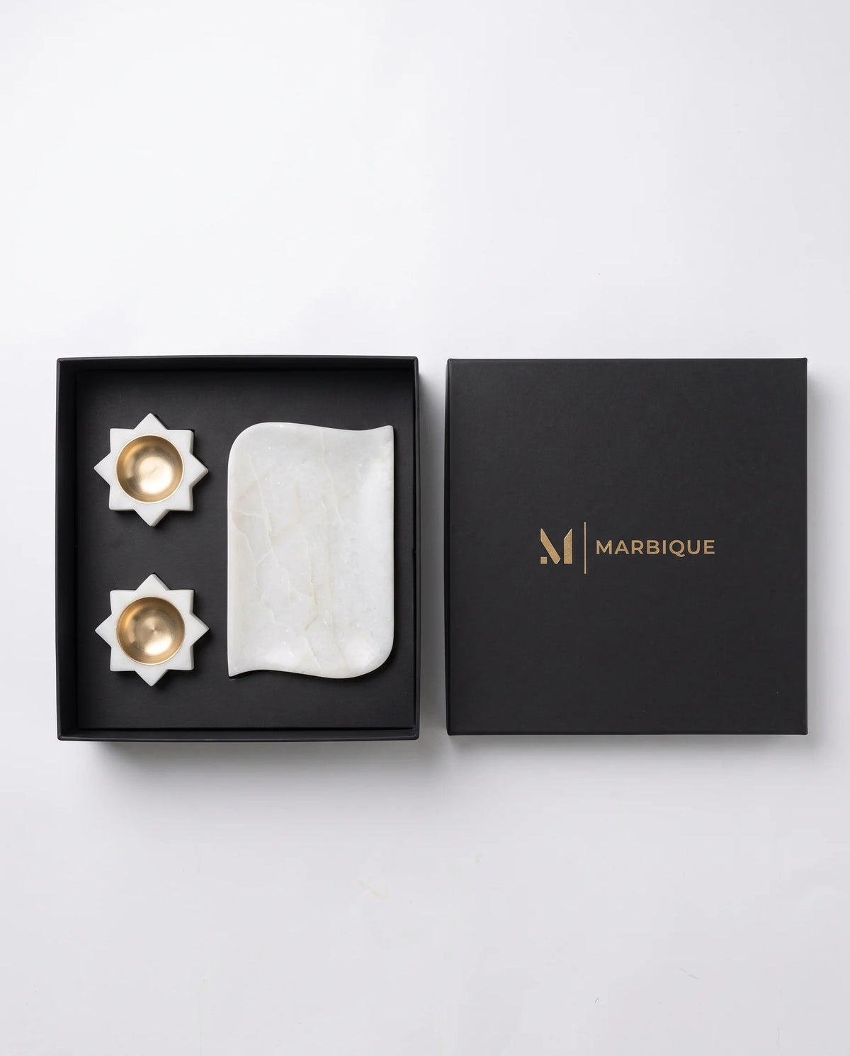 Close view of a plain white scalloped tray and matching holders with circular gold-tone cups.