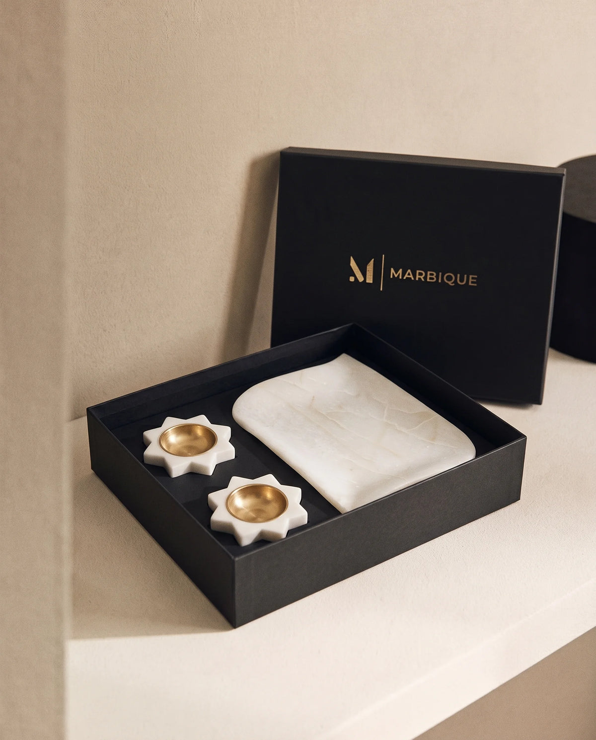 Overhead view of the white scalloped rectangular tray and floral holder arrangement in a black box.