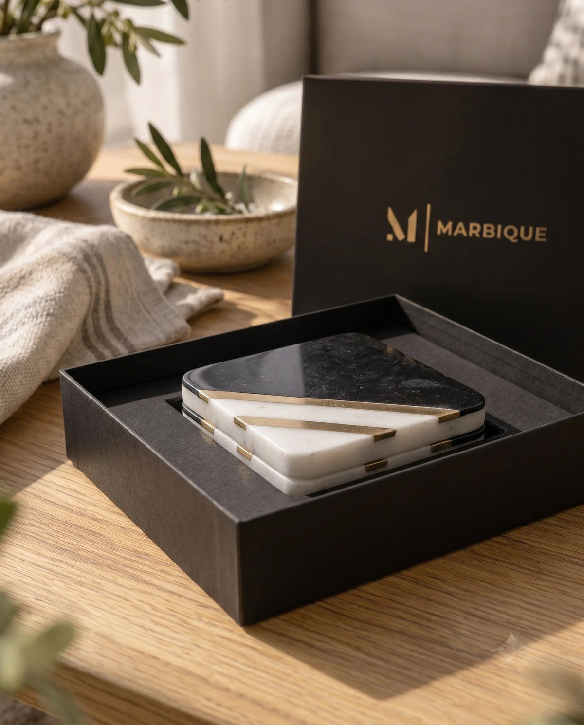 Black and white rounded-square coaster with diagonal gold-tone details in a table setting.