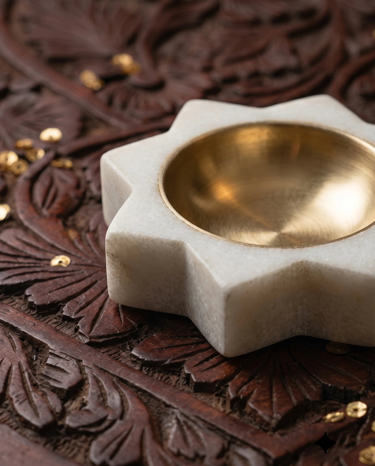 Close-up of a white pointed-star diya-holder base and its round gold-tone cup.