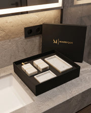 White rectangular bathroom accessory designs with gold-tone bands displayed in a black Marbique presentation box.