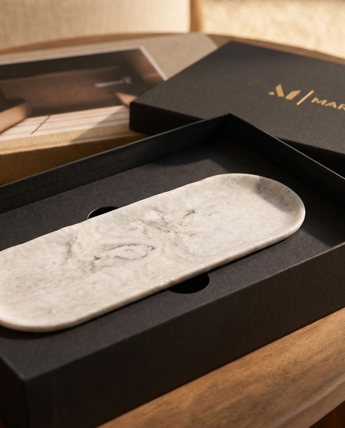 Elongated white oval tray presented with black Marbique packaging.