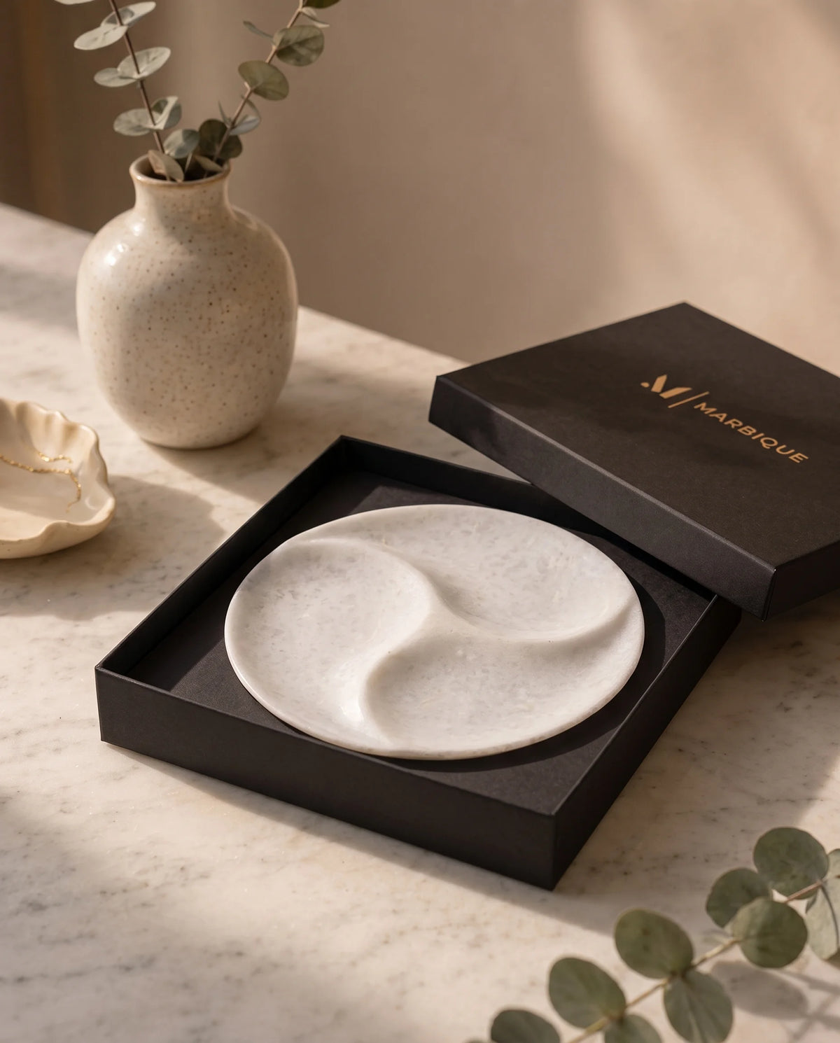 White round tray with three curved recessed sections inside a black Marbique box.