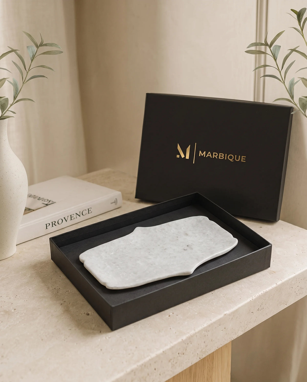 White elongated tray with inward-curving sides and shaped ends in a black Marbique box.