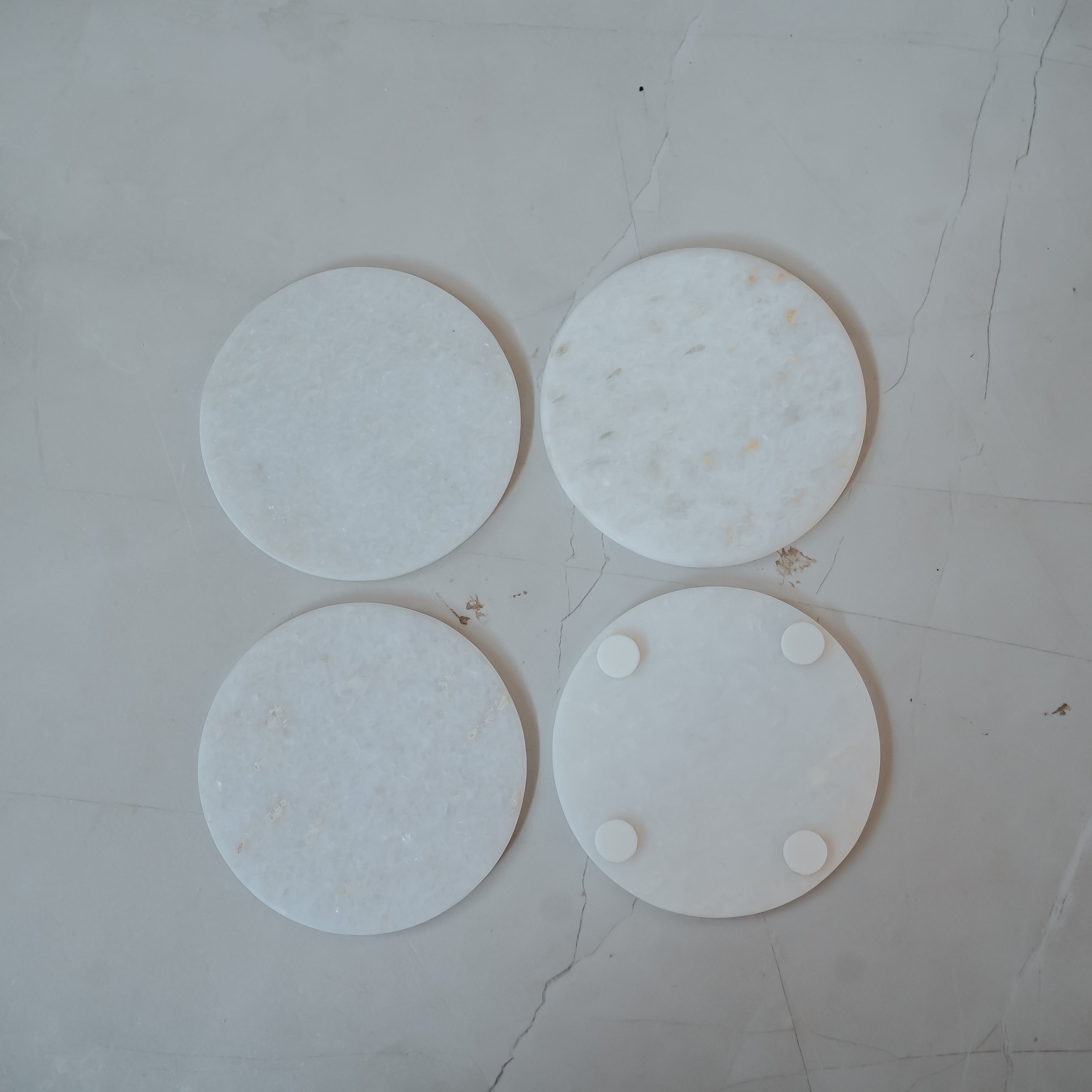 Set of 4 white marble round coasters with natural gray veining pattern overhead product view