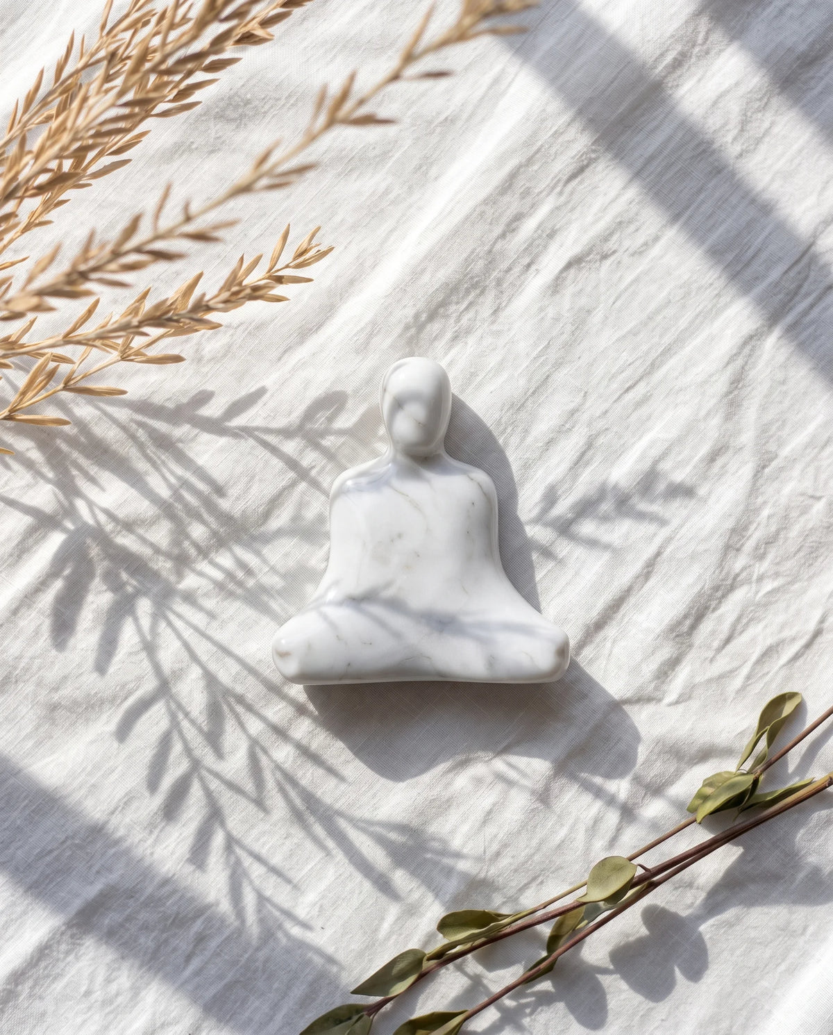Overhead view of the white seated figure and broad crossed-leg outline on light fabric.