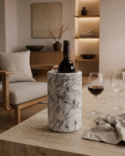 White bottle holder with dark branching veins, styled with a bottle and wine glasses on a light table.