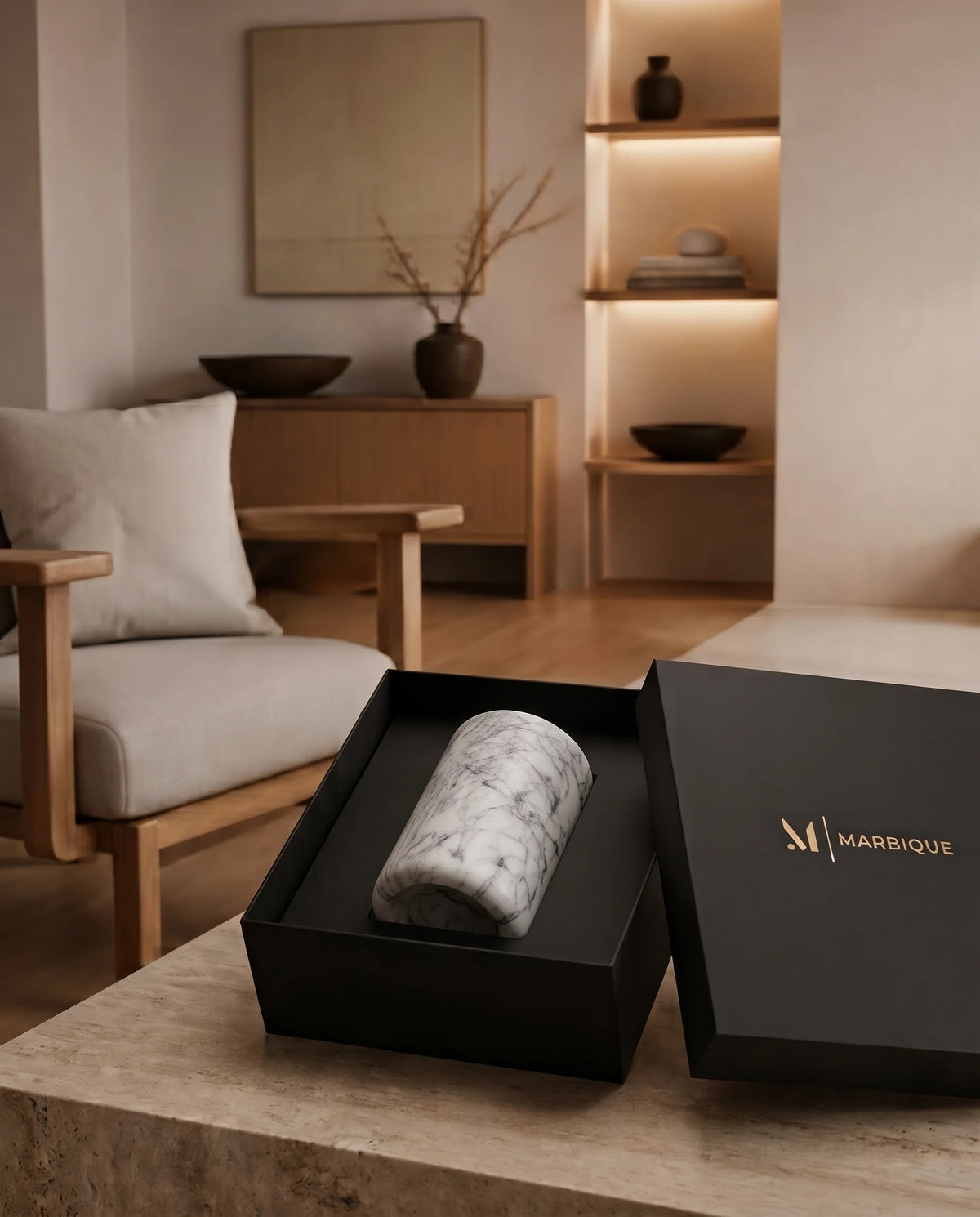 White dark-veined cylinder resting on its side inside black Marbique presentation packaging.