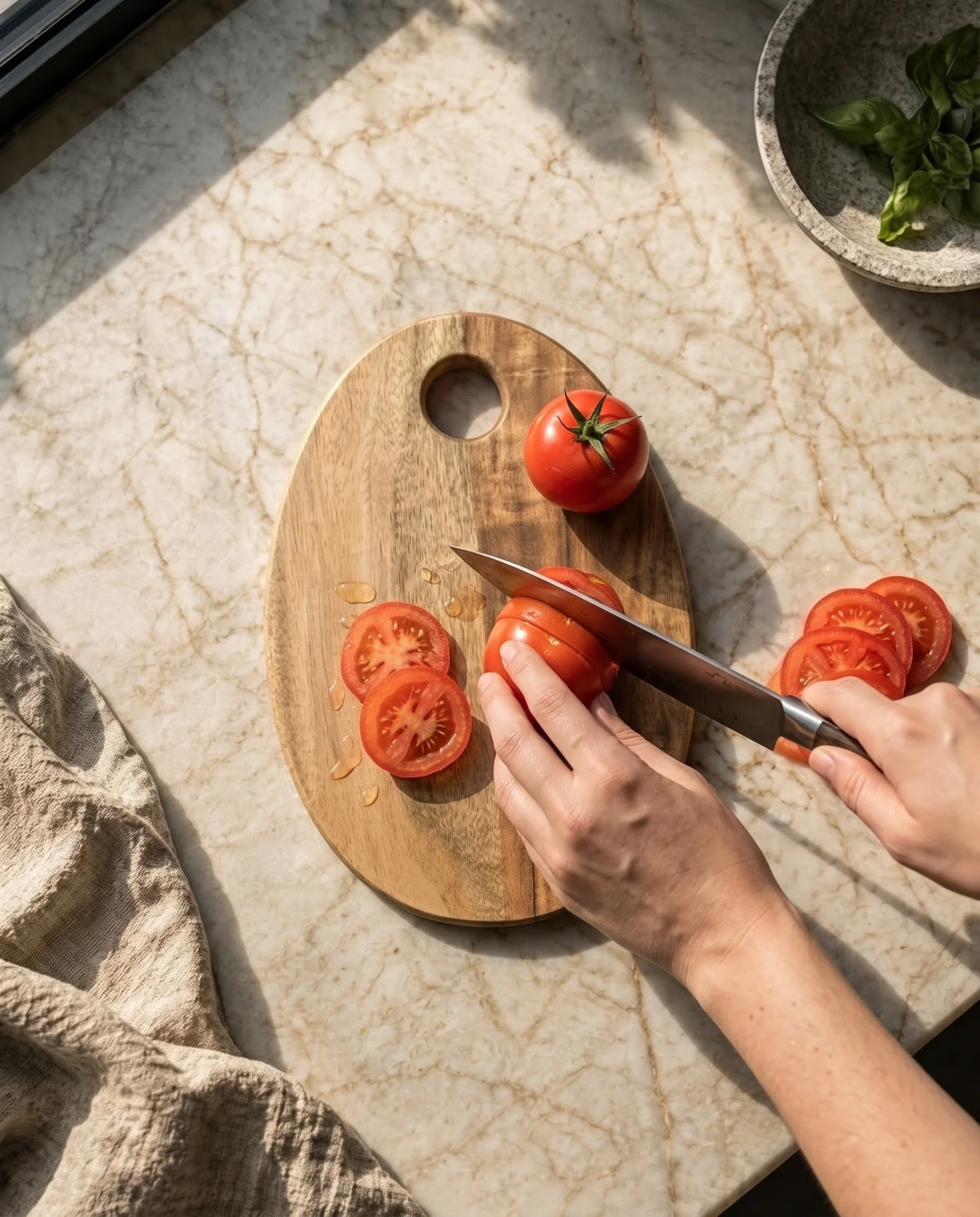 Hands shown slicing a tomato on the two-tone oval board beside a circular opening.