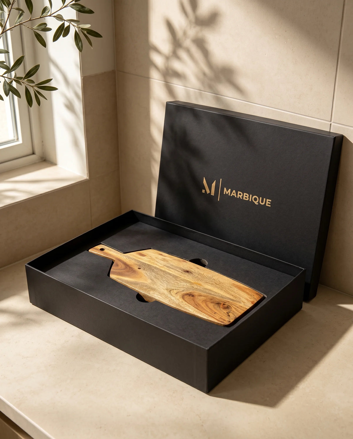 Brown paddle-shaped board with a long narrow handle inside a black Marbique box.
