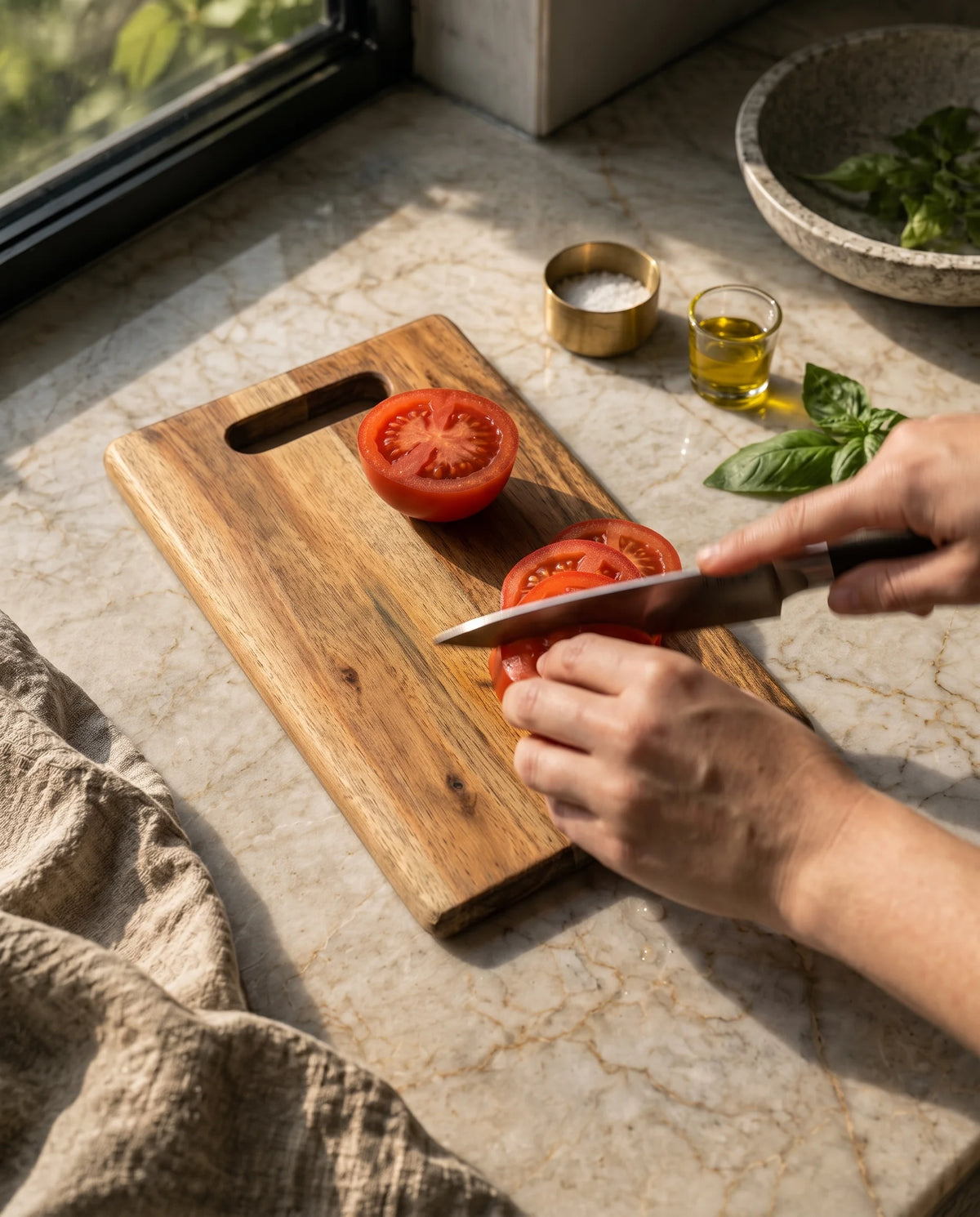 Hands shown slicing a tomato on a brown rectangular board with a slotted grip.