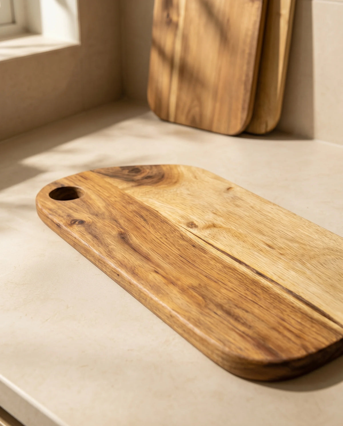 Close-up of contrasting grain-like lines and a circular corner hole on a brown rounded board, with other boards in the background.